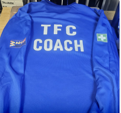 A red and white t-shirt hanging on a chain-link fence.